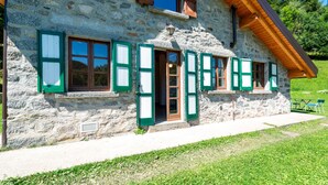 Un edificio de piedra con contraventanas verdes, techo de madera y un cartel con el número 24.