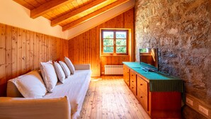 Una cabaña acogedora con paredes de madera y techo inclinado, un sofá con cojines, una mesita y un televisor.