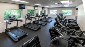 Un gimnasio con cintas de correr, elípticas y máquinas de pesas.