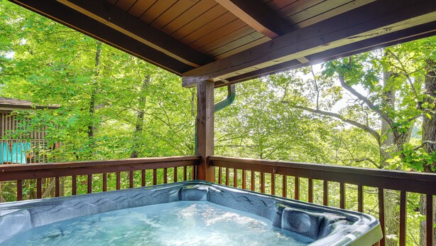 A hot tub on a wooden deck with a view of a lush green forest. - Community Pool! Sevierville Stay w/ Hot Tub (Sevierville)