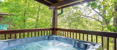 Un bain à remous sur une terrasse en bois, avec vue sur une forêt.