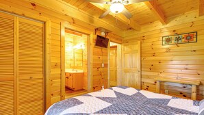 A wooden cabin room with a bed, a ceiling fan, and a wooden bench. - Community Pool! Sevierville Stay w/ Hot Tub (Sevierville)
