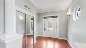 Un passadís amb una porta de vidre, una paret blanca amb el rètol 'Home' i una finestra rodona.