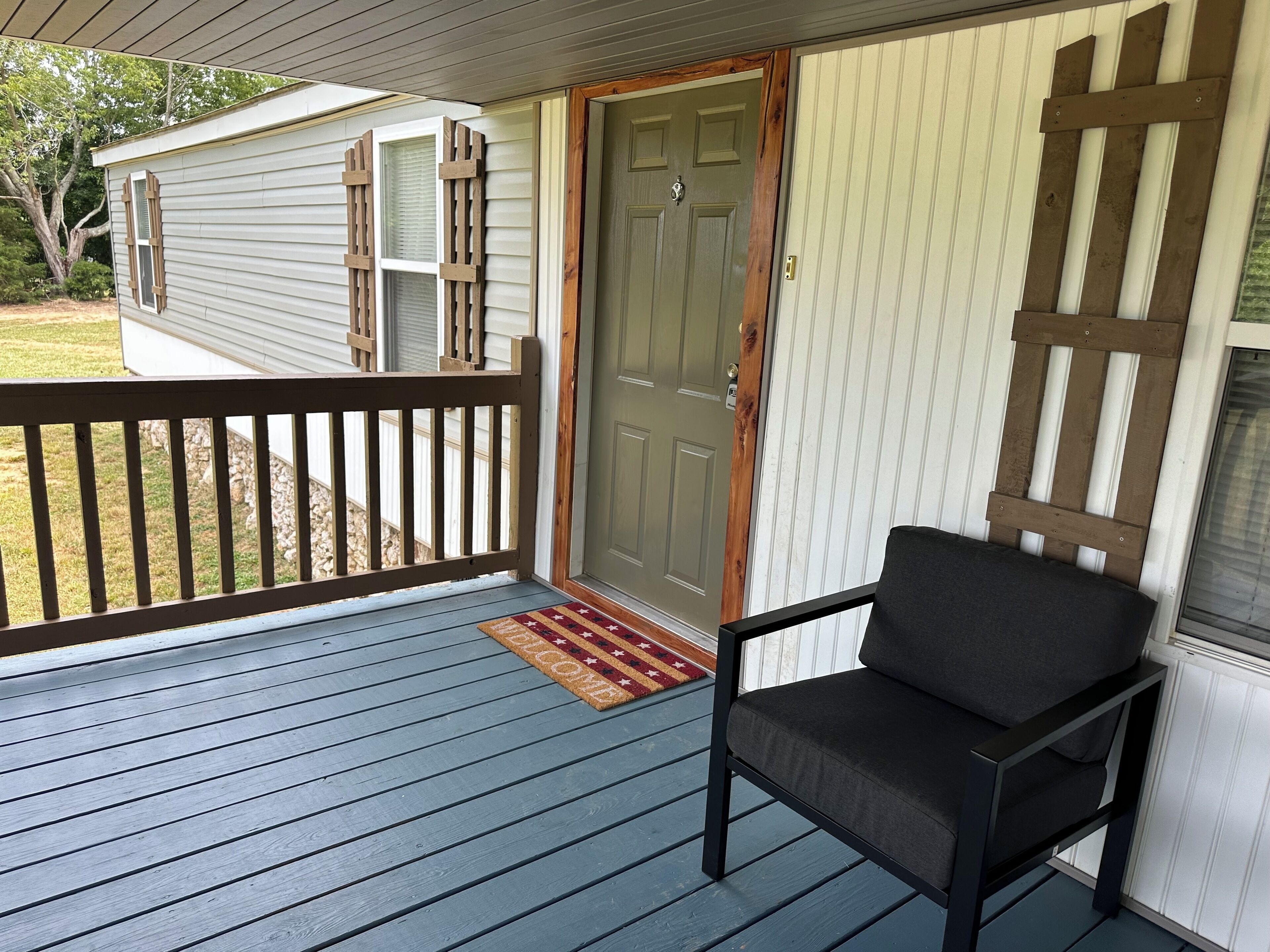 A porch with a wooden railing, a door, and a chair.