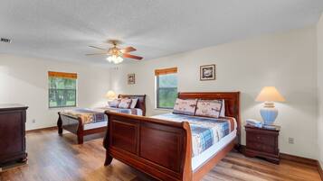 A bedroom with two wooden beds, a ceiling fan, and a nightstand with a lamp.