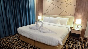 Une chambre d’hôtel avec un grand lit, deux lampes de chevet, une tête de lit ornée d’un motif géométrique et un rideau bleu.