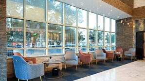 Un espace intérieur spacieux avec de grandes fenêtres, des chaises modernes et un mur en pierre.