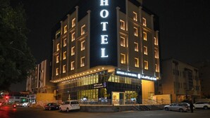 Un hôtel à plusieurs étages, doté d’une enseigne lumineuse, d’une entrée imposante et d’une façade bien éclairée.