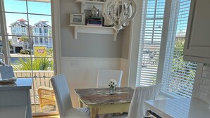 A kitchen with a wooden table, white chairs, a chandelier, and a view of the outside.