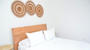 Un lit bien fait, avec du linge de lit blanc, une tête de lit en bois et trois éléments de décoration circulaire accrochés au mur.