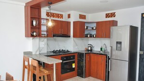 Une cuisine moderne avec des meubles en bois, un réfrigérateur en acier inoxydable et une cuisinière à gaz.