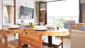 Un salon moderne comprenant un coin repas, de grandes fenêtres, un téléviseur à écran plat et un balcon avec vue.
