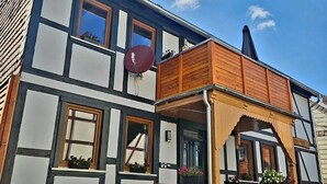 En traditionel bindingsværksbygning med en træbalkon og en parabolantenne.