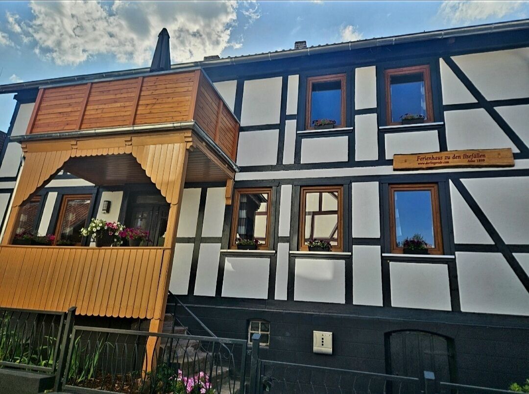 Un bâtiment traditionnel à colombages, doté d’un balcon en bois et de jardinières fleuries.