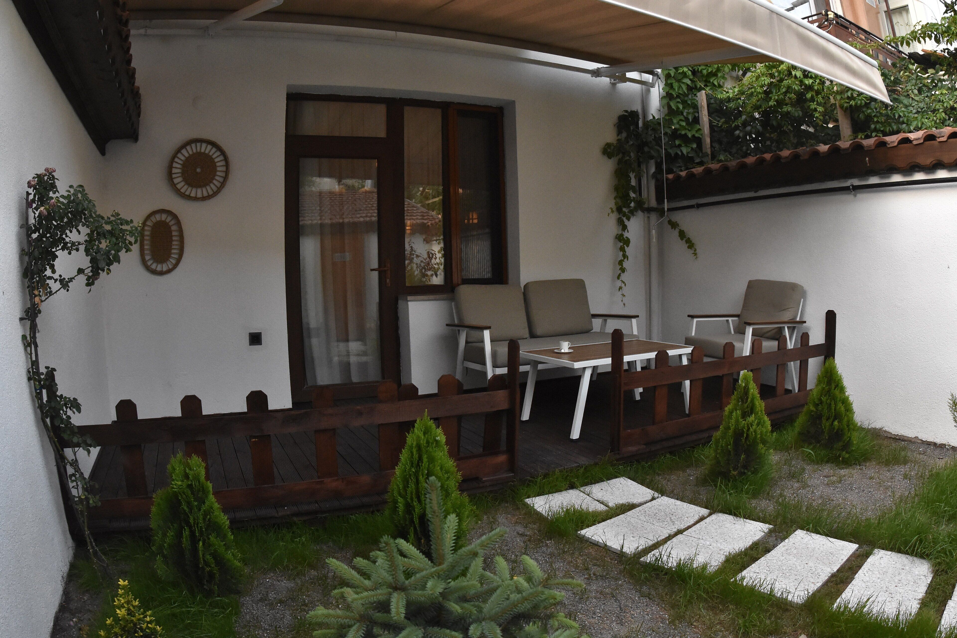 Un patio con valla de madera, una mesa con sillas y plantas en macetas.