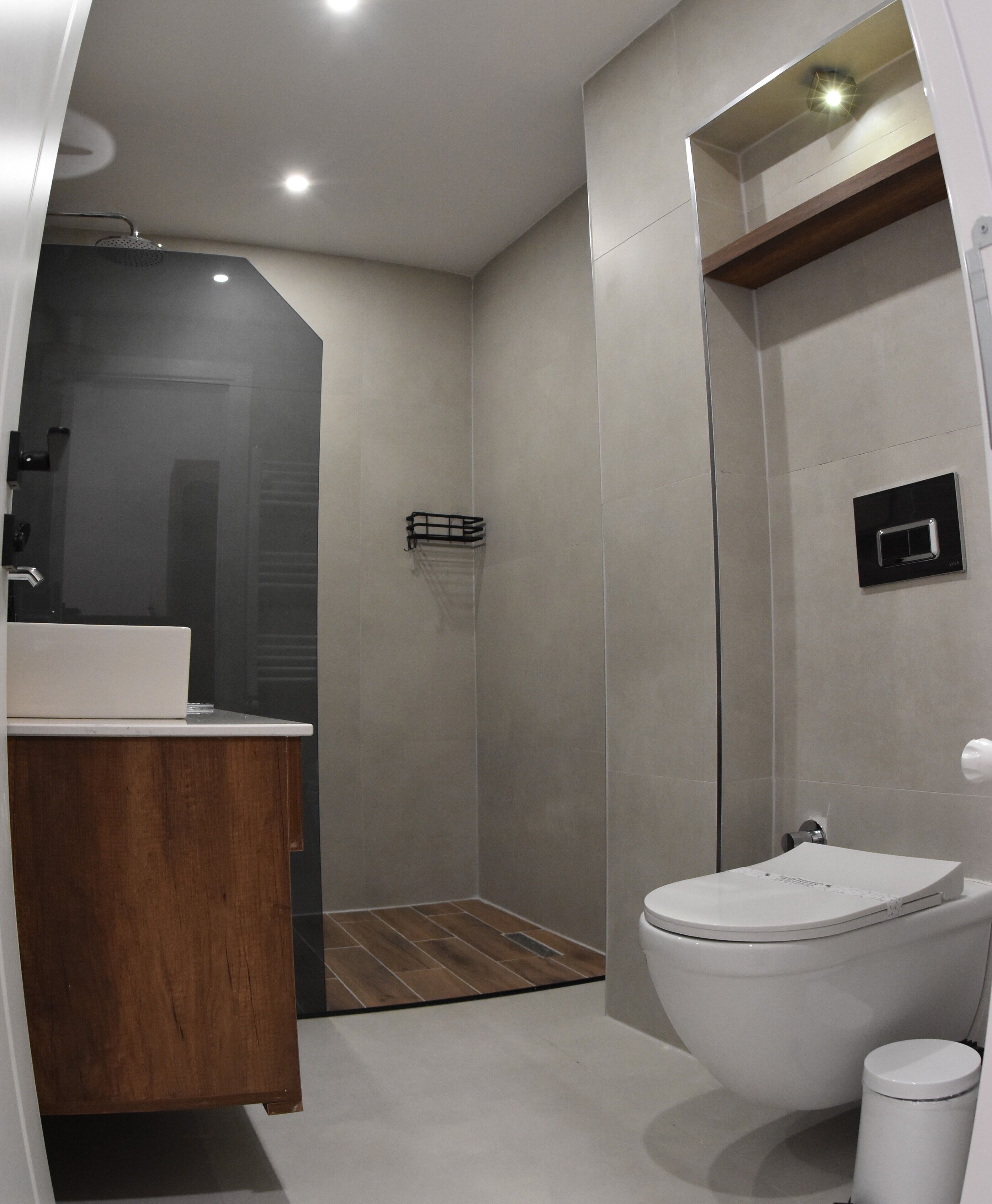 Une salle de bain moderne avec un meuble-lavabo en bois, des toilettes et un espace douche.
