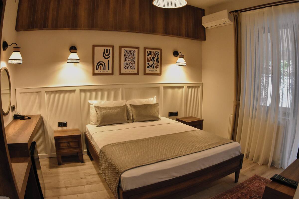 A bedroom with a bed, bedside tables, a mirror, and wall art.