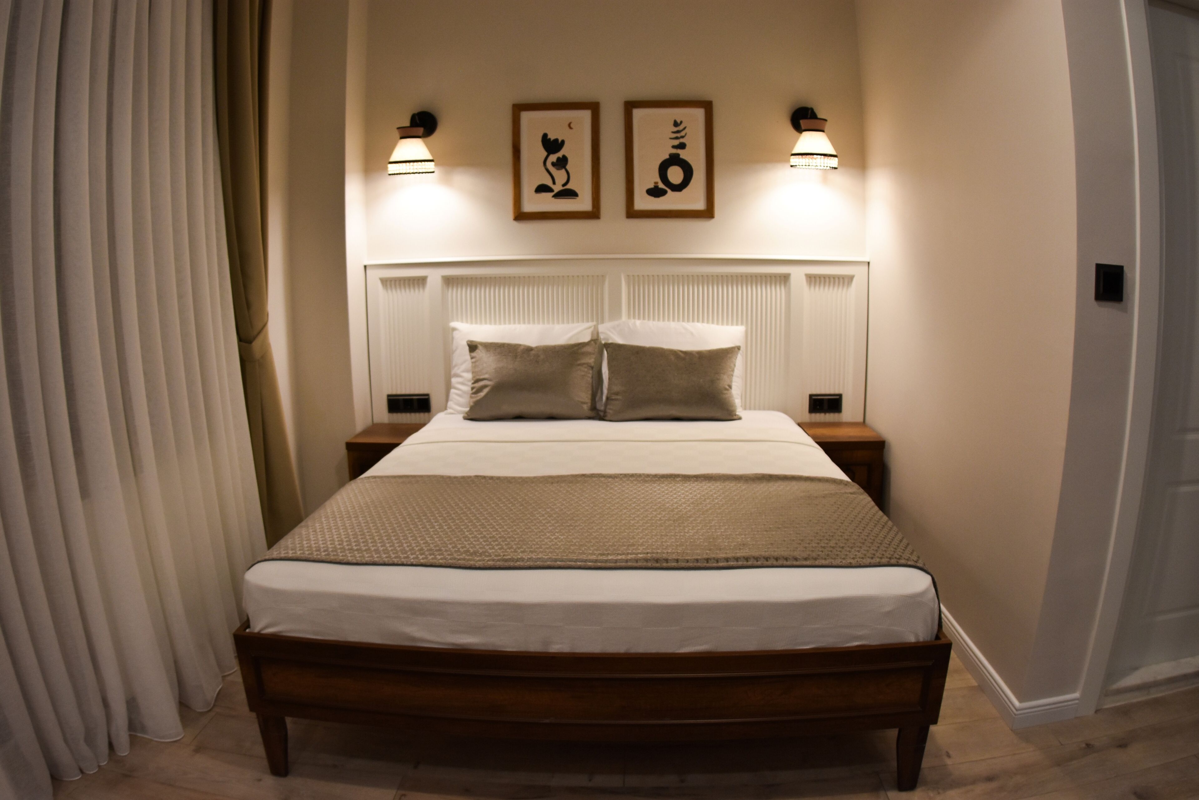 A neatly made bed with a wooden frame, two bedside tables, and wall-mounted lamps.