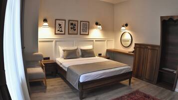 Een slaapkamer met een bed, nachtkastjes, een stoel, een radiator, een spiegel en een deur.