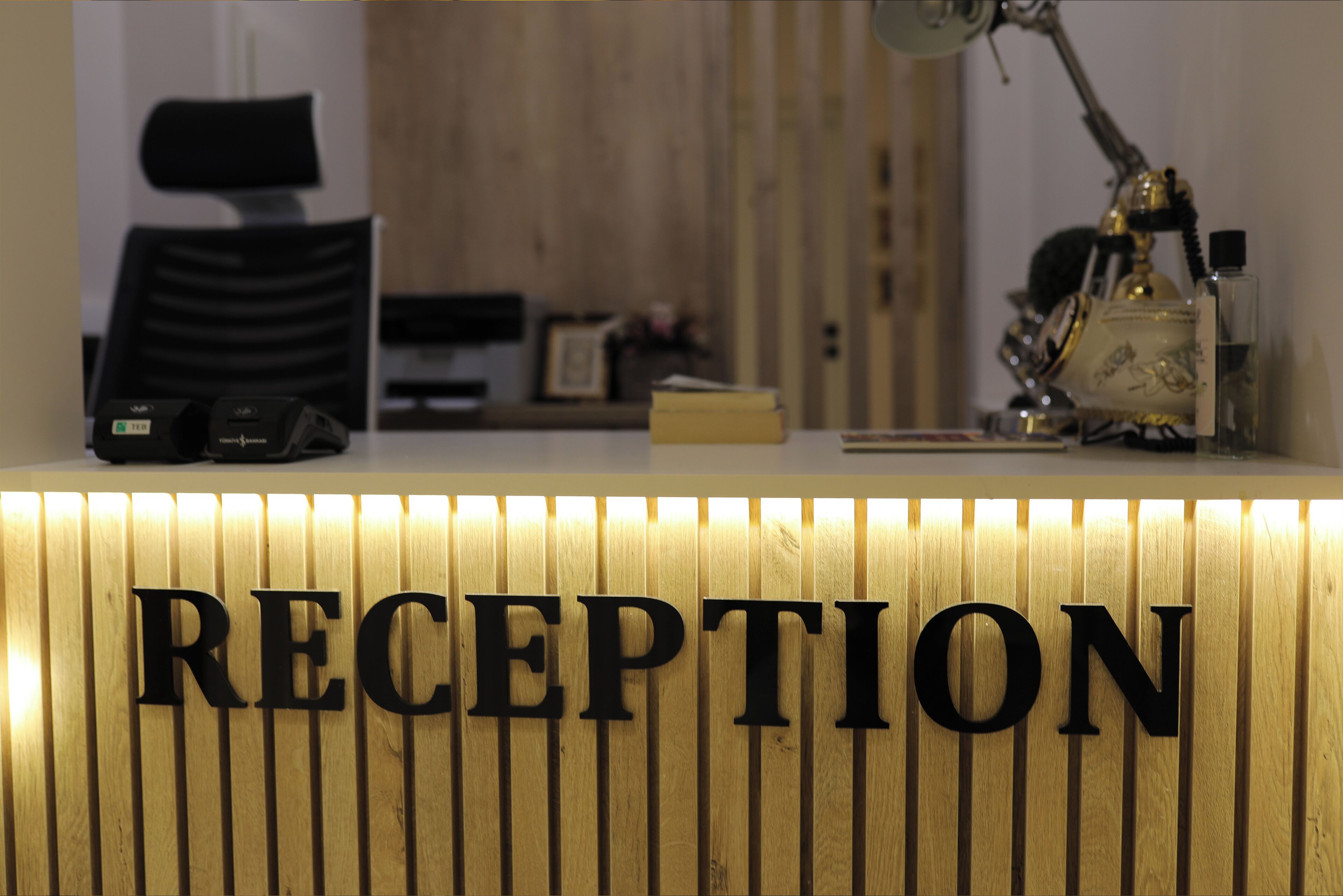 A reception desk with a wooden panel and the word "RECEPTION" in large letters.