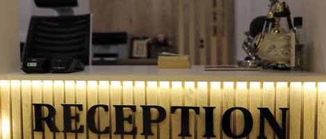 A reception desk with a wooden panel and the word "RECEPTION" in large letters.