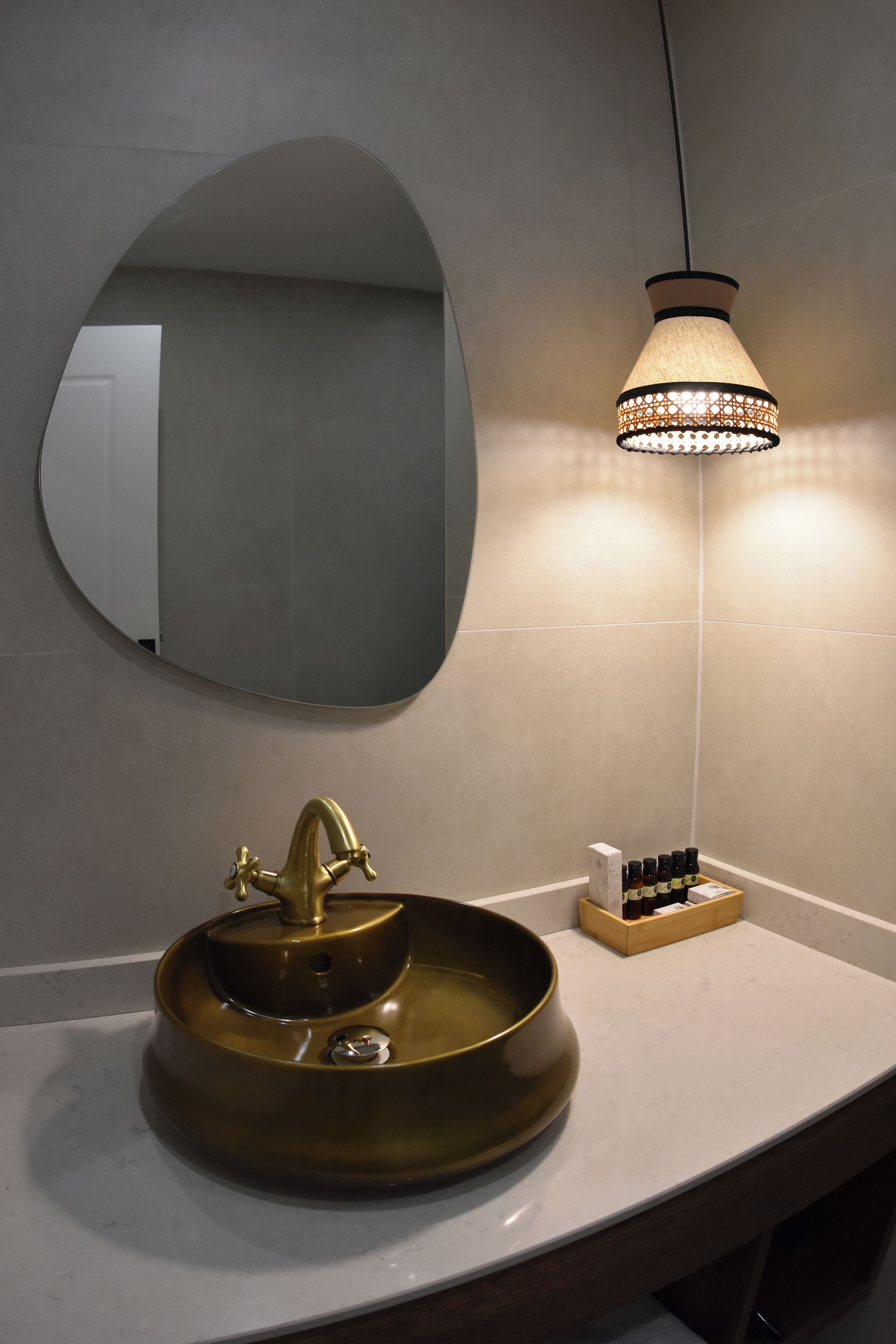 A bathroom with a round sink, a mirror, and a pendant light.