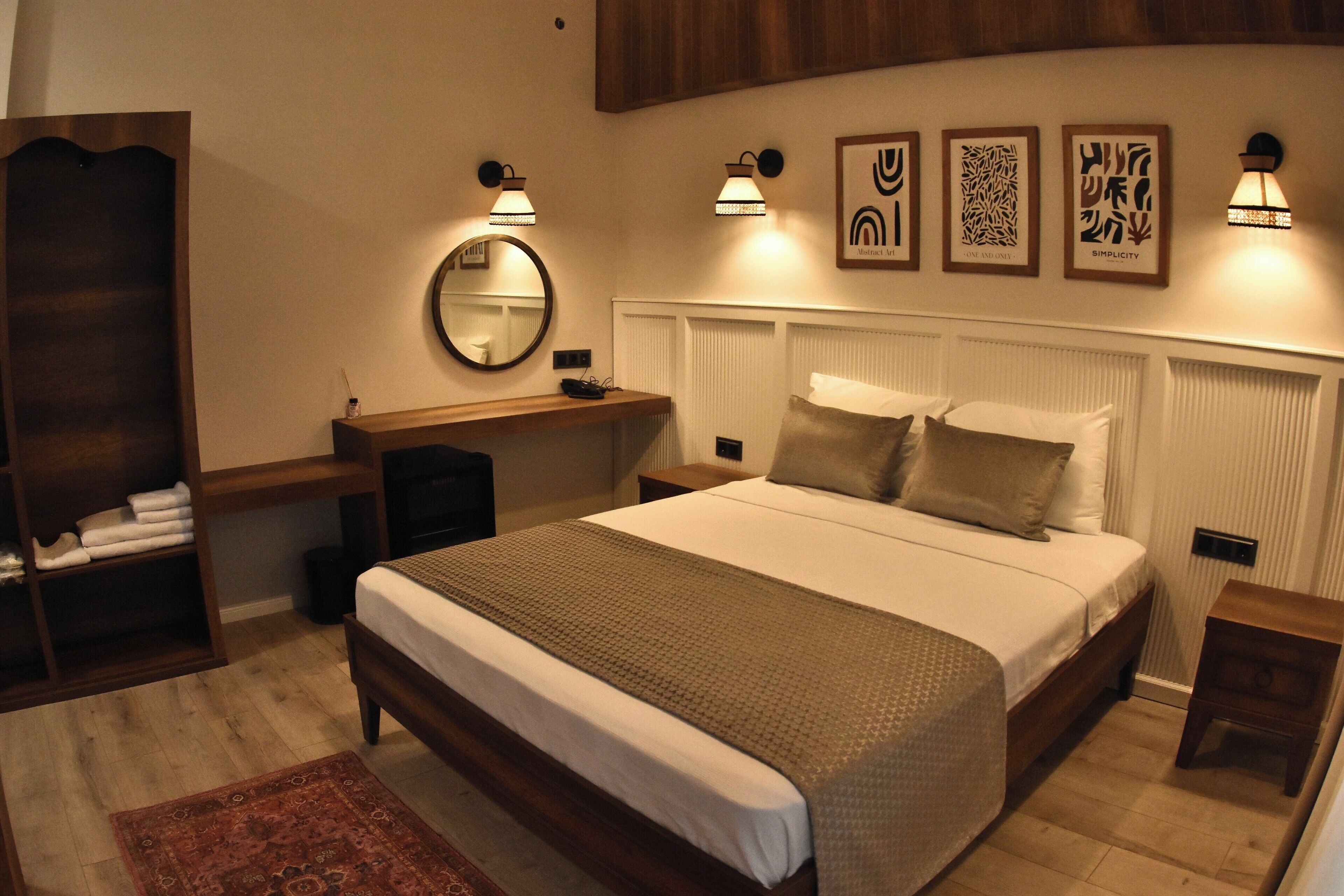 A bedroom with a large bed, bedside tables, a mirror, and wall-mounted lights.
