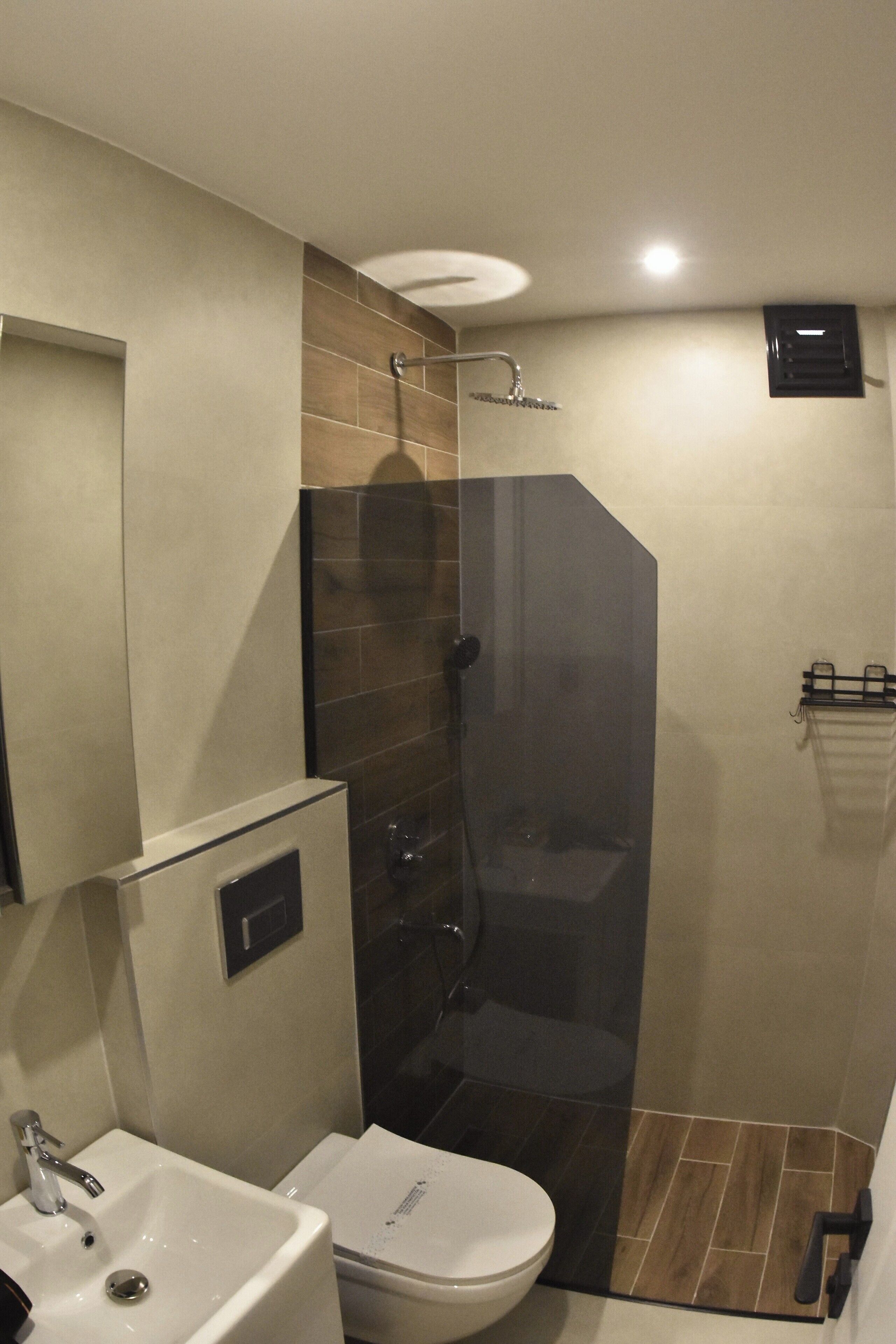 A modern bathroom with a glass-enclosed shower, a sink, and a toilet.