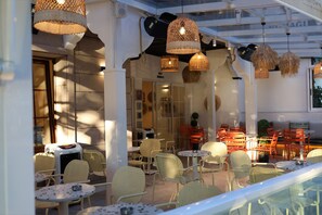 An outdoor seating area with wicker lamps, yellow and orange chairs, and tables. - Amasya Atabey Konağı (Amasya)