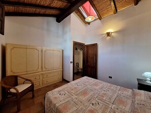 Une chambre à coucher avec un lit, une armoire en bois, une chaise et un luminaire au plafond.