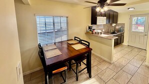 Une cuisine équipée d’une table à manger, de chaises, d’un ventilateur de plafond et d’un four à micro-ondes.