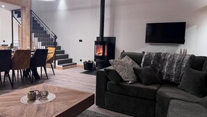 A modern living room with a sofa, a coffee table, a fireplace, a TV, and a staircase. - JARDIN ALPIN 1 - LA PLAGNE TARENTAISE (LA PLAGNE TARENTAISE)