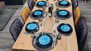 A dining area with a wooden table set for six, surrounded by leather chairs. A coffee machine and a small cabinet are visible in the background. - JARDIN ALPIN 1 - LA PLAGNE TARENTAISE (LA PLAGNE TARENTAISE)