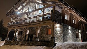 A multi-level wooden cabin with stone walls and a balcony, surrounded by snow. - JARDIN ALPIN 1 - LA PLAGNE TARENTAISE (LA PLAGNE TARENTAISE)