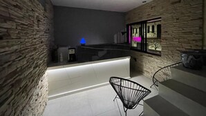 A modern kitchen with a stone wall, a black countertop, and a blue lamp.