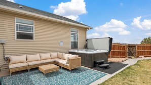 Een beige huis met een patio, voorzien van een beige modulaire bank, een rieten stoel en een jacuzzi.