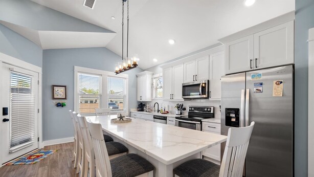 A modern kitchen with white cabinetry, stainless steel appliances, and a marble island.
