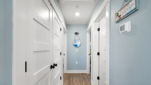 A hallway with white doors, a wooden floor, and a wall-mounted mirror.
