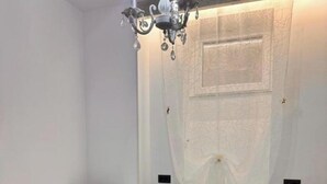 A bedroom with a bed, a chandelier, and a window with a sheer curtain. - Old arhitectura center Bucharest Universitate  (București)