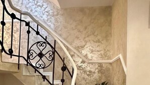 A marble staircase with a wrought iron railing, leading to a landing with a potted plant. - Old arhitectura center Bucharest Universitate  (București)