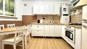 A compact kitchen with white cabinets, a wooden dining table, and a built-in oven. - Old arhitectura center Bucharest Universitate  (București)