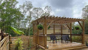 Une terrasse en bois avec une piscine, entourée d’une clôture en bois et agrémentée de plantes en pot.