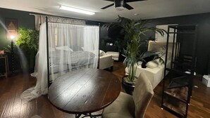 Une pièce comprenant un lit, un ventilateur de plafond, une table et des chaises.