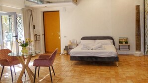 Une chambre spacieuse avec un grand lit, une table à manger en verre et une vue sur l’extérieur.