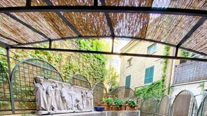Un patio couvert doté d’un sol en pierre, d’une table avec des chaises et d’une sculpture décorative en pierre.