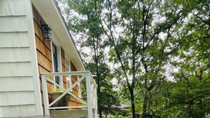 Een pad dat leidt naar een huis met een veranda, omringd door bomen en groen.