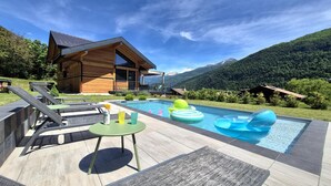 A modern house with a pool, lounge chairs, and inflatable rings. - CHALET DES EPICURIENS (AIME LA PLAGNE)