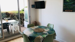 Un comedor con una mesa redonda, sillas y vistas a un patio exterior a través de un ventanal.