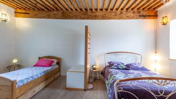 A bedroom with two wooden beds, a small white cabinet, and a wooden ceiling.