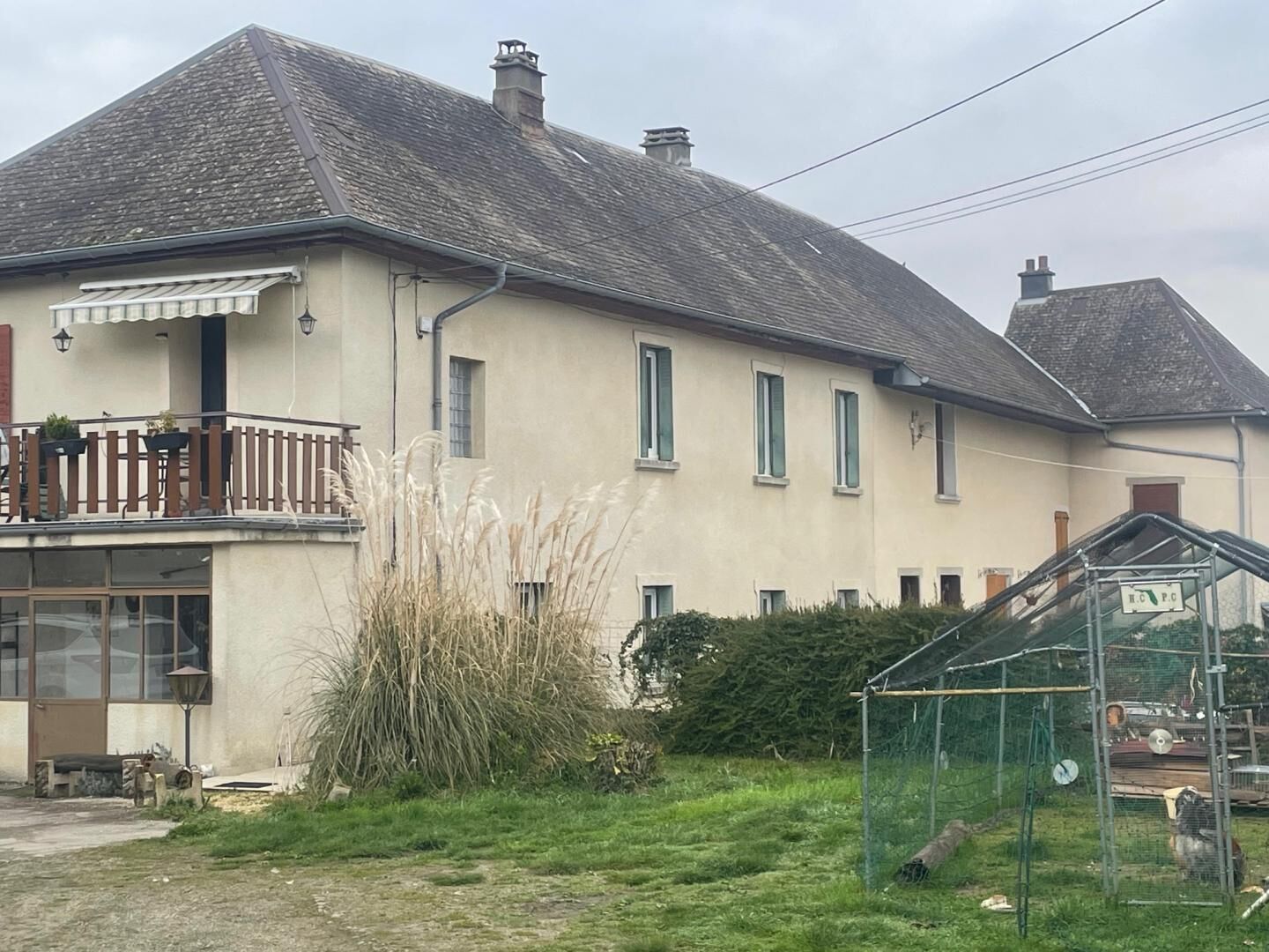 Une maison à deux étages avec un balcon, un petit jardin et une serre.